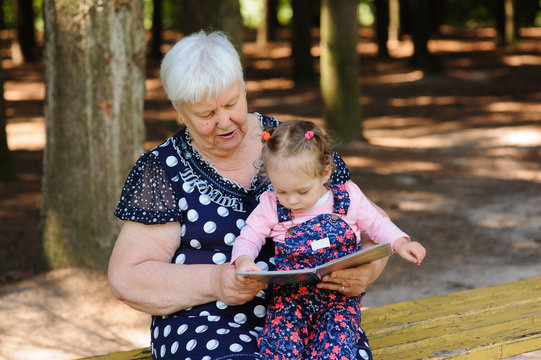 Grandmother and granddaughter reading the book in the park