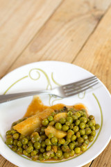 Cooked peas with potatoes on the retro old wooden table