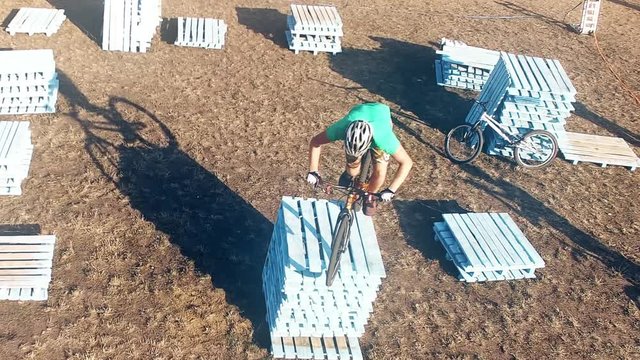 Сyclist doing jump MTB tricks in bicycle 4k aerial video. Mountain bike trial rider in park. Extreme sport lifestyle