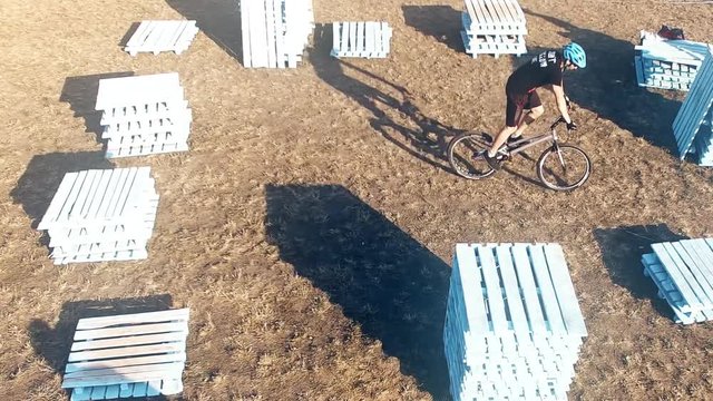 Two cyclists doing jump MTB tricks in bicycle 4k aerial video. Mountain bike trial rider in pallet park. Extreme sport lifestyle