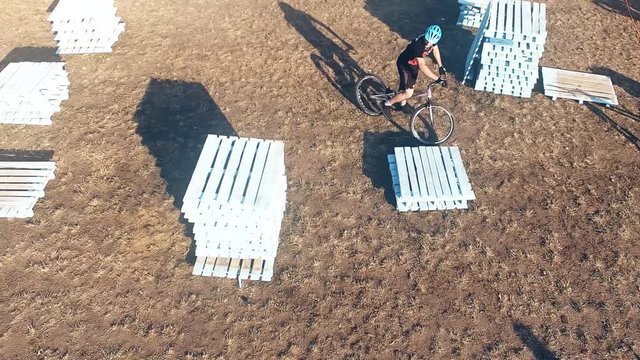 Сyclist doing jump MTB tricks in bicycle 4k aerial video. Mountain bike trial rider in park. Extreme sport lifestyle