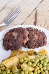 Served minced meat steaks with peas and potatoes
