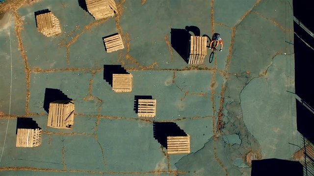 Сyclist doing jump MTB tricks in bicycle 4k top view aerial video. Mountain bike trial rider in box park. Extreme sport lifestyle