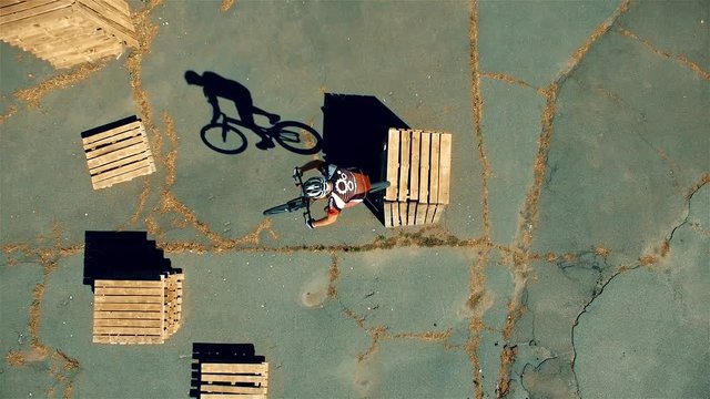Сyclist doing jump MTB tricks in bicycle 4k top view aerial video. Mountain bike trial rider in box park. Extreme sport lifestyle