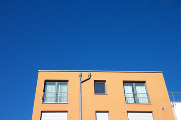 Closeup of an orange apartment building against a blue sky