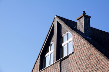 Fototapeta na wymiar House with red bricks and windows next to chimney under roof