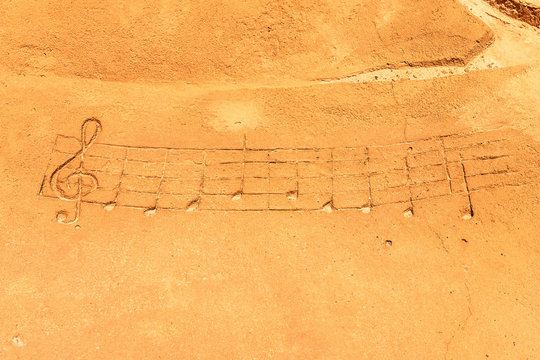 Drawn musical notes on a sandy beach
