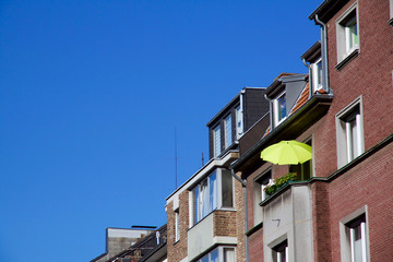 Fototapeta na wymiar Row of houses, one with a sunshade on balcony for a relaxed evening, against a blue sky in Aachen, Germany