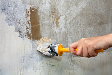 Close-up, hands holds paintbrush, worker painting  wall with whi