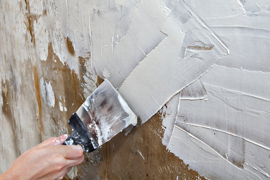 Aligning wall painters putty, painter hands holding steel spatul