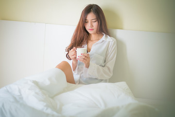 Fototapeta na wymiar Beautiful brunette woman drinking and morning coffee in bedroom