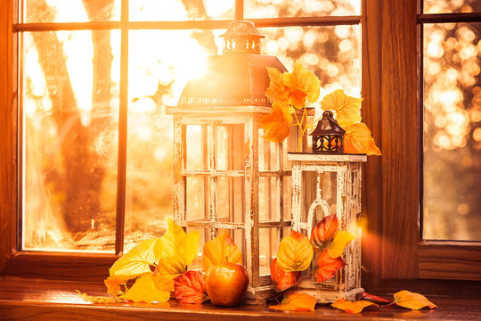 Vintage lanterns, autumn leaves and red apple in evening sun shine. Closeup