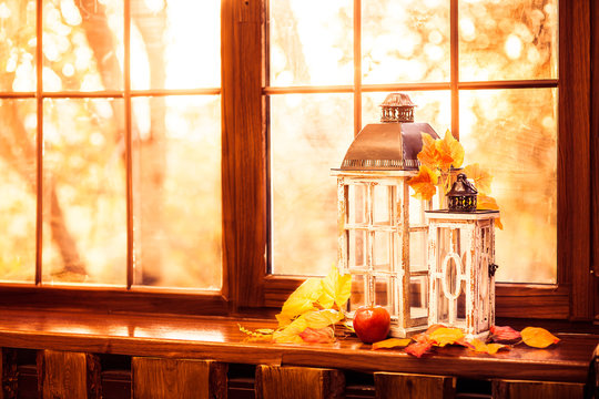 Vintage lanterns, autumn leaves and red apple in evening sun shine.