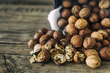 Fresh walnuts spill out of a wicker basket on autumn background on the old wooden table, healthy eating cocept, selective focus