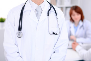 Close-up of a male doctor in a background of doctor and patient