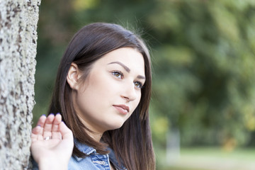  A young woman leaning on a tree