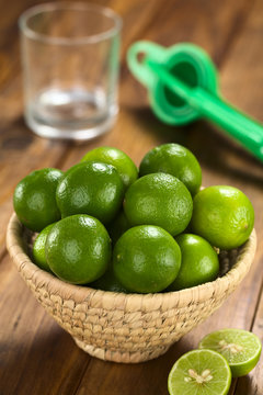 Limes in woven basket with lime squeezer and glass in the back (Selective Focus, Focus on the two upper limes)