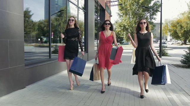 Three lovely young women walking down the street and enjoying their shopping day