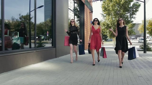 Three wonderful female friends walking down the street and talking to each other