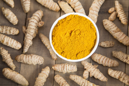 Turmeric in bowl on wooden background