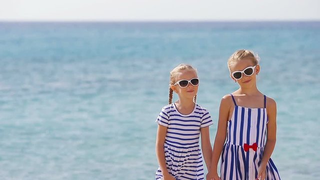 Adorable little girls ooking at camera together during beach vacation. Kids enjoy summer vacation in greek beach