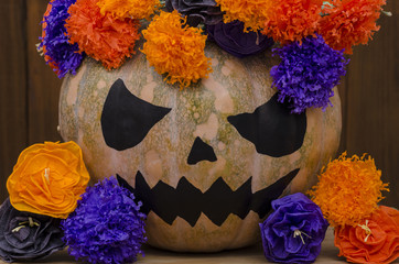 Halloween pumpkin on wooden background with colorful flowers