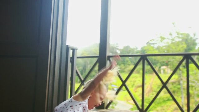 Little Blond Girl Runs out Barefoot to Balcony from Dark Room