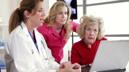 A pretty physician using a laptop to discuss test results with an elderly patient and her daughter.