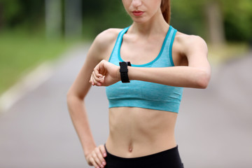 Young woman checking time after run in park