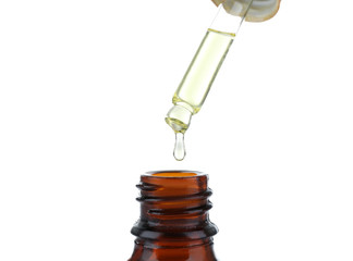 Mint oil dripping from pipette into glass bottle on white background