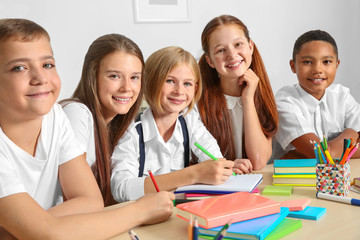 Schoolchildren drawing while sitting at table in classroom