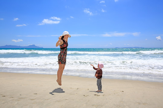 Young pretty woman with little daughter having fun on Sandy Beach