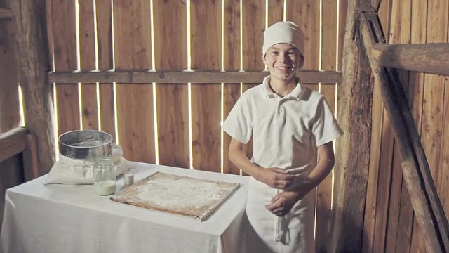 Little boy in apron after making bread in the small wood house