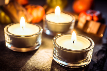 Halloween Decoration With Three Tea Lights, Chocolate And Pumpkins On Slate