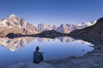 Woman watching Alps mountain range and beautiful reflection in lake
