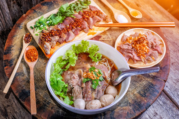 Thai noodle soup with sliced beef and beef meatballs on big wood cutting board