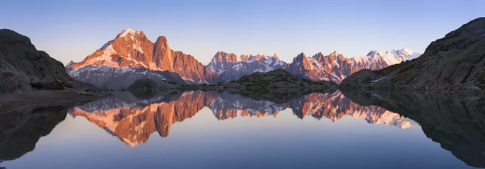 Panorama der Alpenberge mit Sonnenuntergangslicht, das sich im See widerspiegelt © NicoElNino