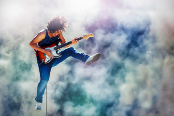 rock star guitarist jumping and playing electric guitar