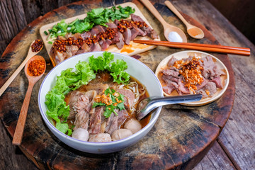 Thai noodle soup with sliced beef and beef meatballs on big wood cutting board