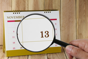 Magnifying glass in hand on calendar you can look Day Thirteen o