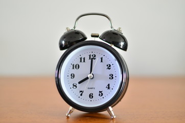 The black alarm clock is showing time at eight o'clock