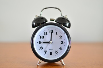 The black alarm clock is showing time at nine o'clock