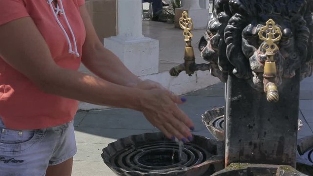 Female hand washes under the tap in the street