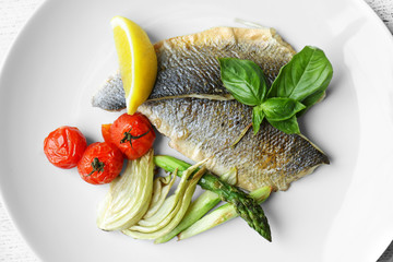 Grilled fish with vegetables on white plate