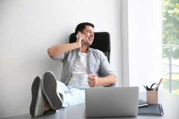 Handsome man talking on mobile phone and drinking coffee