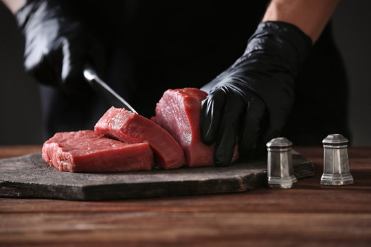 Butcher cutting pork meat on kitchen