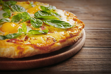 Margarita pizza with basil leaves and egg on wooden background