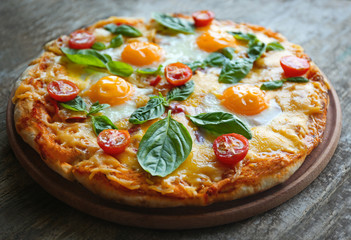 Margarita pizza with basil leaves and egg on wooden background