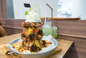 Waffle chocolate ice cream with various fruit and whip cream on zinc tray