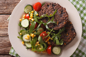 Vegetarian black bean burgers and fresh vegetable salad closeup. horizontal top view
